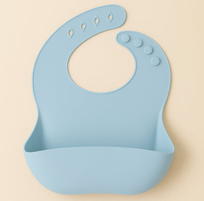 Loomie silicone bib with adjustable neck strap and front pocket, designed for meal time protection and easy cleaning.